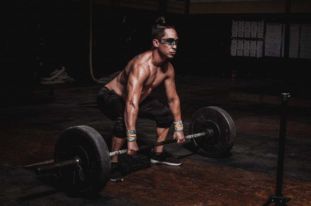 shirtless man lifting barbell