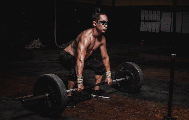 shirtless man lifting barbell